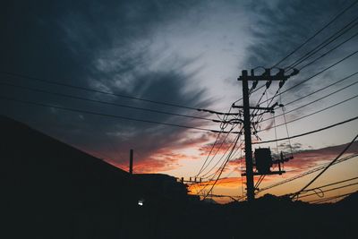 Low angle view of silhouette electricity pylon against sky