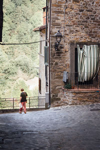 Rear view of woman walking on street against building