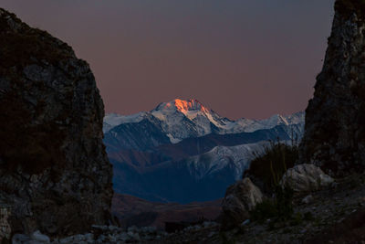 Sunset illuminates the mountain. scenic view of snowcapped mountains against sky