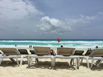 Chairs on beach against sky