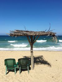 Chairs on beach against clear blue sky