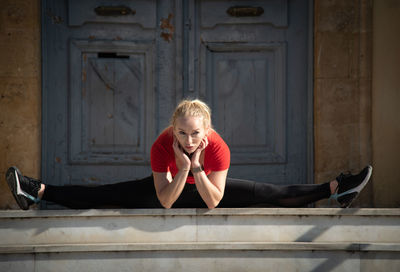 Side view of young woman sitting on wall