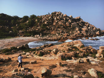 Rear view of people on rock by sea against sky