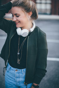 Close-up of smiling young woman standing on mobile phone