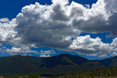 Scenic view of mountains against stormy clouds