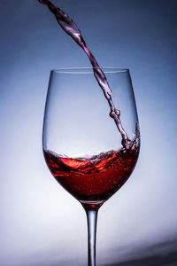 Close-up of wineglass on glass against white background