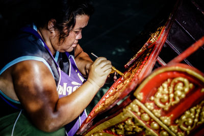 Side view of female artist working on wood at workshop