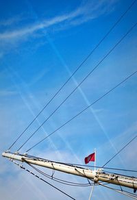 Low angle view of electricity pylon against blue sky