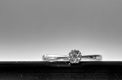 Close-up of diamond ring on table against gray background