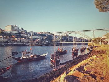 Boats moored on river by city against clear sky