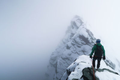 Rear view of woman standing on cliff amidst fog