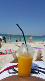 Close-up of drink on beach against clear blue sky