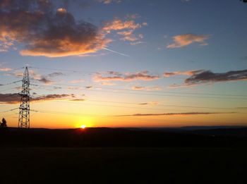 Scenic view of silhouette field against orange sky