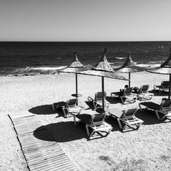 Lounge chairs on beach against sky