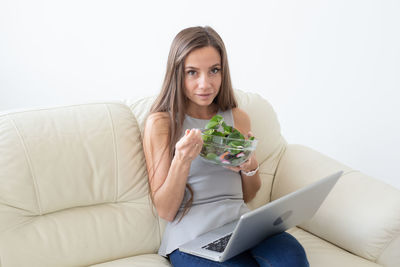 Portrait of young woman using phone while sitting on sofa