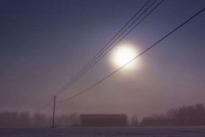 Power lines against sky at sunset