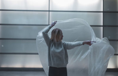 Midsection of woman standing against white wall