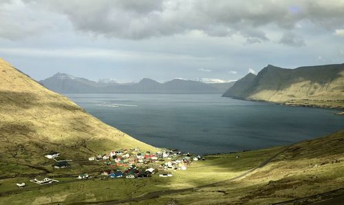 People on shore by mountains against sky