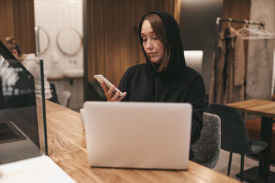 Adult  serious business woman freelancer working in a coffee shop cafe using a laptop and phone