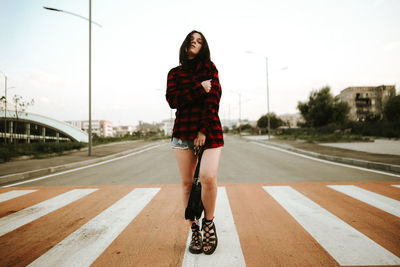 Full length of fashionable young woman on zebra crossing in city