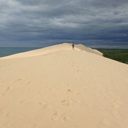 Man walking on sand at beach against sky