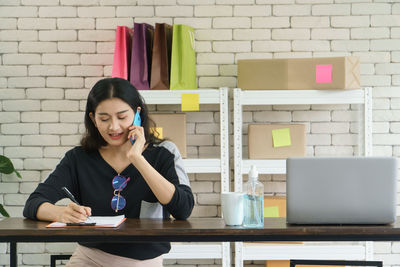 Young woman using phone while sitting on table