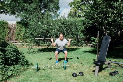 Man working out at home in the garden with his home gym equipment