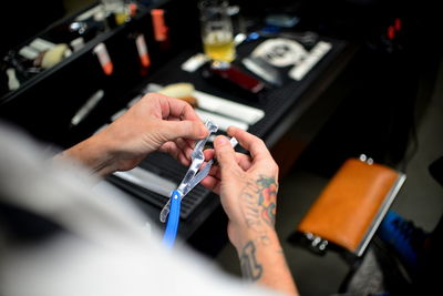 Close-up of tattooed hand of a barber holding straight razor