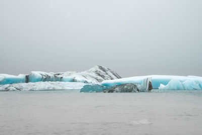 Scenic view of snow covered landscape against sea