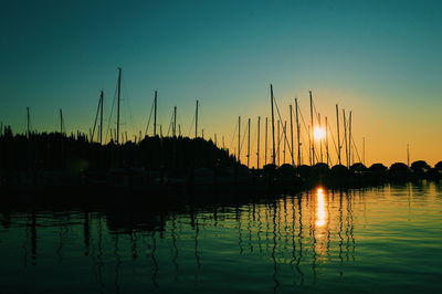 Sailboats in sea at sunset