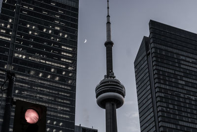 Low angle view of communications tower in city against sky