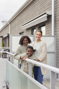 Portrait of mothers and son standing on balcony
