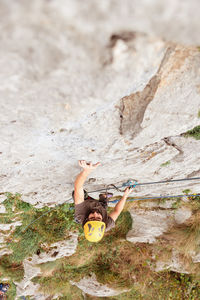Sportive male alpinist climbing on sheer cliff in summer day