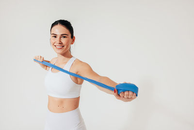 Portrait of young woman exercising against white background