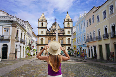 Rear view of woman with arms outstretched standing in city