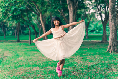 Full length portrait of girl holding dress in park