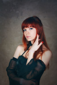 Portrait of beautiful woman with redhead standing against wall