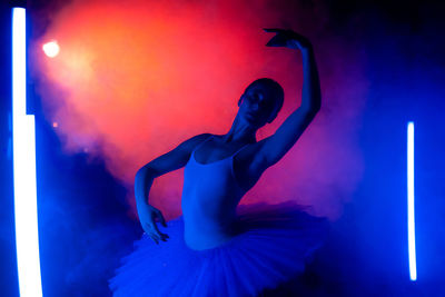 Full length of woman dancing against illuminated light