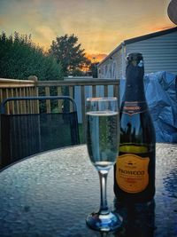 View of drink on table by railing against sky during sunset