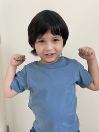 Portrait of smiling boy standing against wall