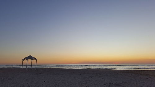 Scenic view of beach against clear sky during sunset