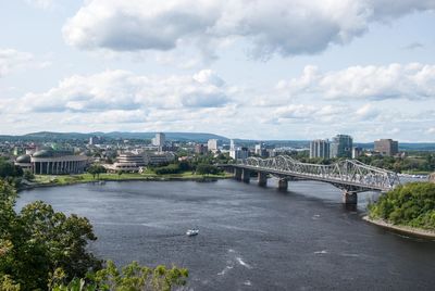 Bridge over river in city against sky