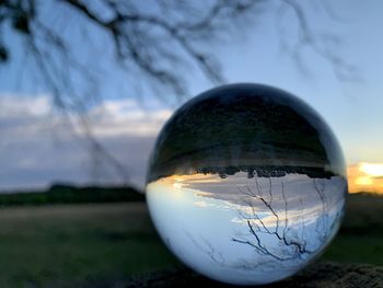 Close-up of crystal ball on field during sunset