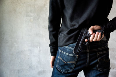 Midsection of man holding hands standing against wall