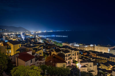 High angle view of illuminated cityscape against blue sky