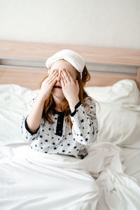 Young woman using mobile phone while lying on bed at home