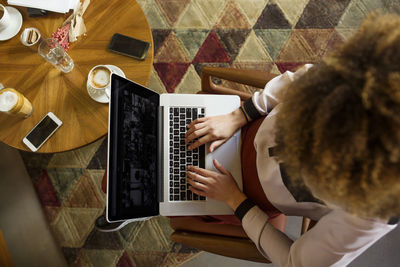 Overhead view of businesswoman using laptop in hotel lobby