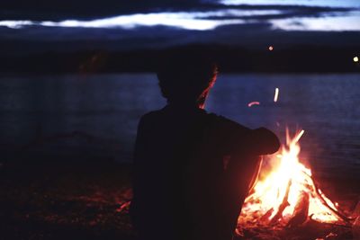 Silhouette person at bonfire in the dark