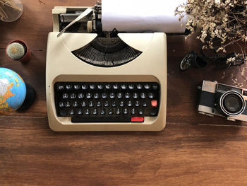Directly above view of typewriter with camera and decors on wooden table