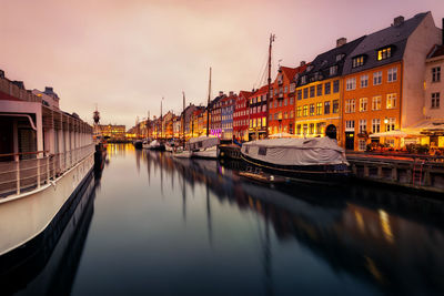 Boats moored in canal amidst buildings in city